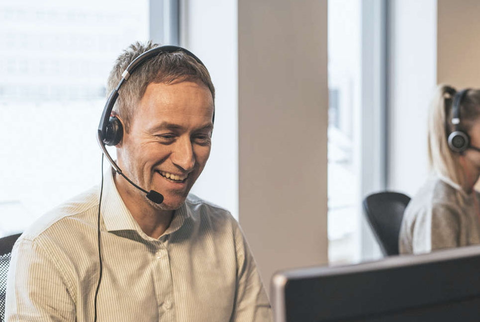 Bilde av en kundeservice-ansatt som smiler mens han tar imot samtaler